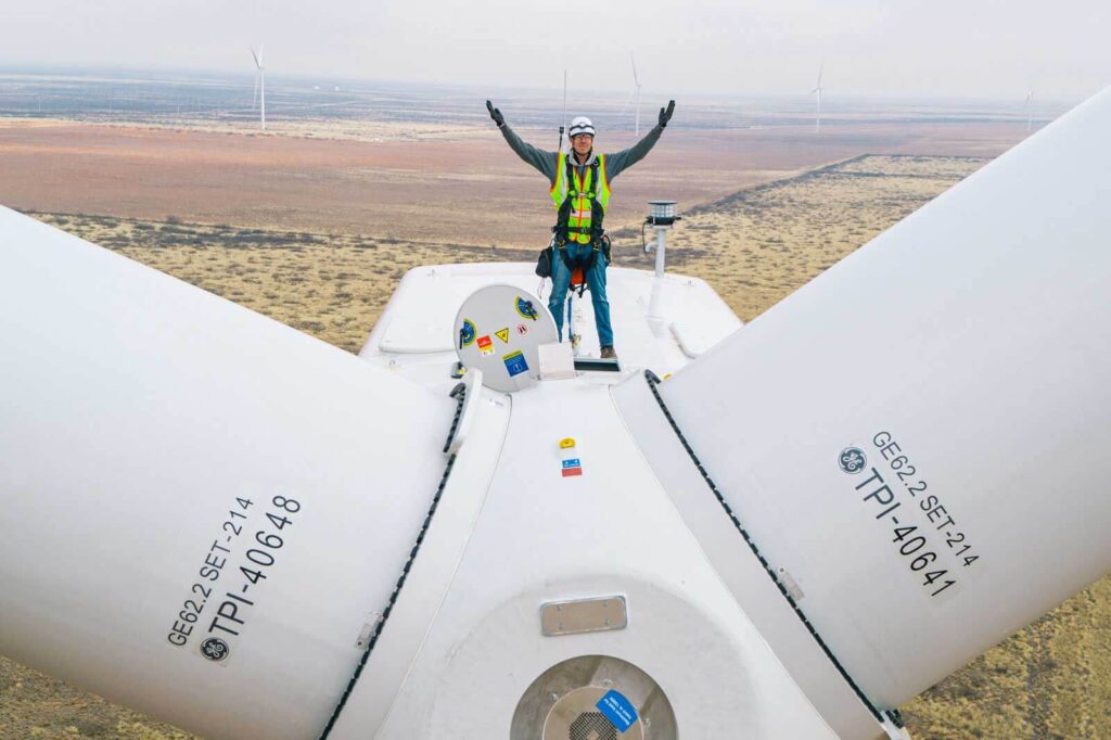 man on top of wind turbine