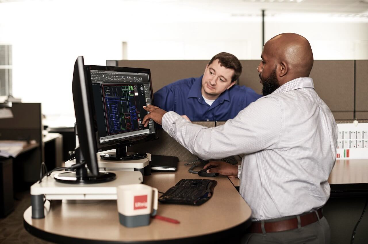 man pointing to computer while another man looks over the screen