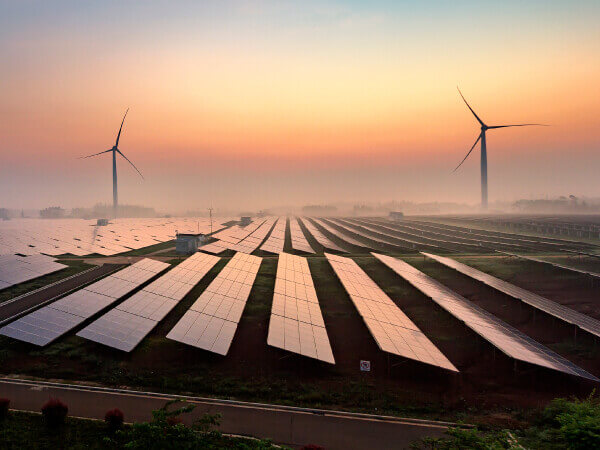 large solar panels and wind turbines with beautiful sunset