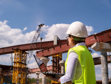woman in hardhat looking at crane at construction sight