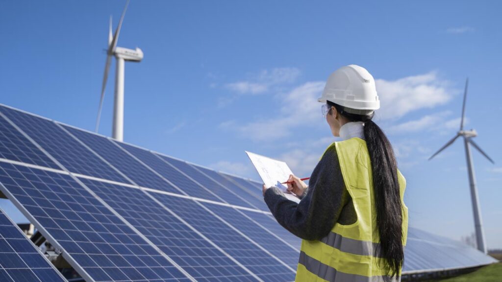 construction worker looking at solar panels and wind turbines