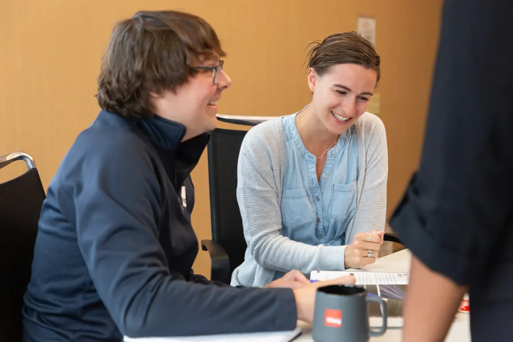 Two people smiling reviewing a document