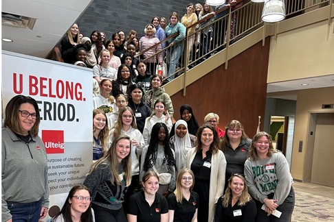 Women gathered on main floor and going up a stairwell around an Ulteig Banner